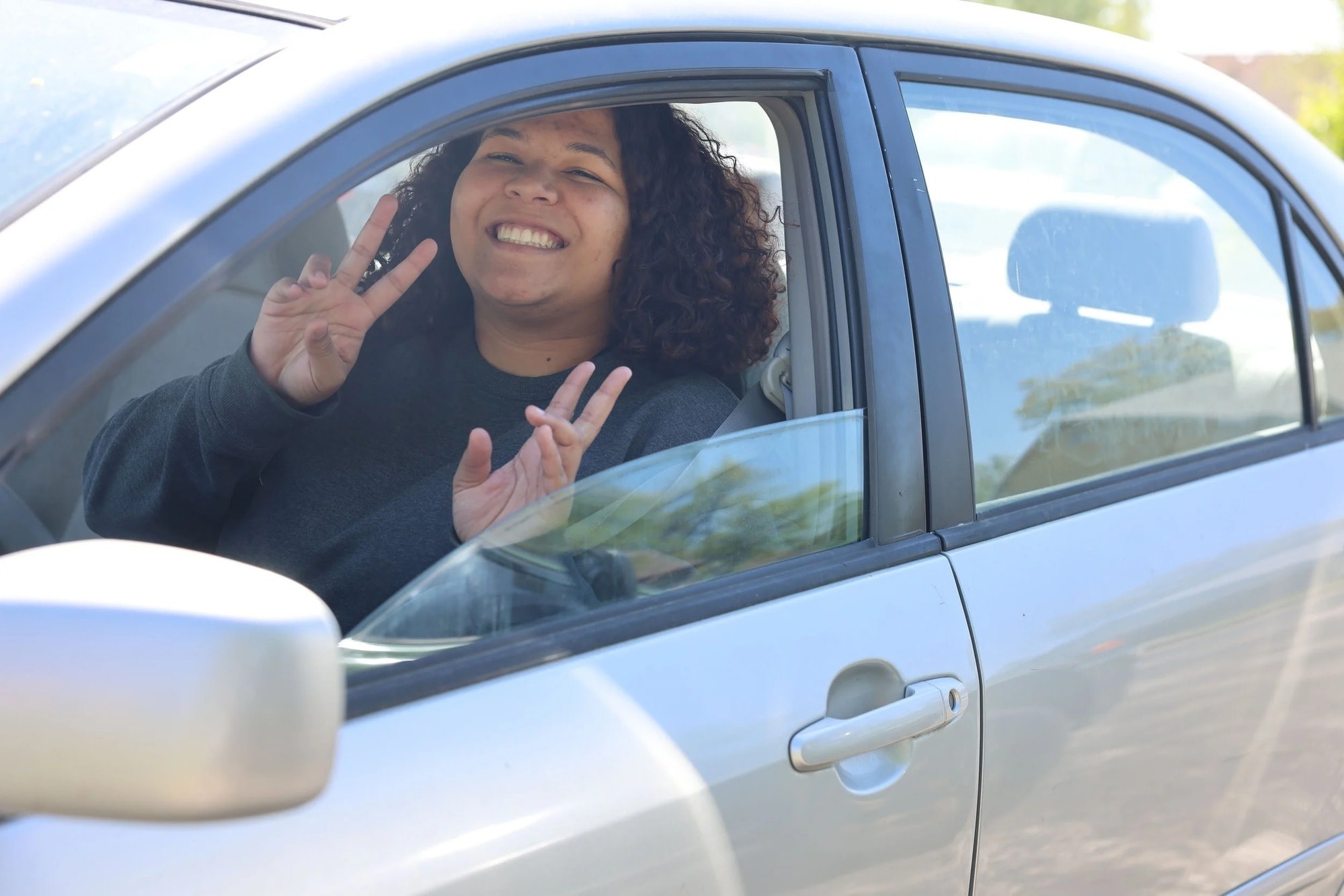 A smiling donor waving from her car